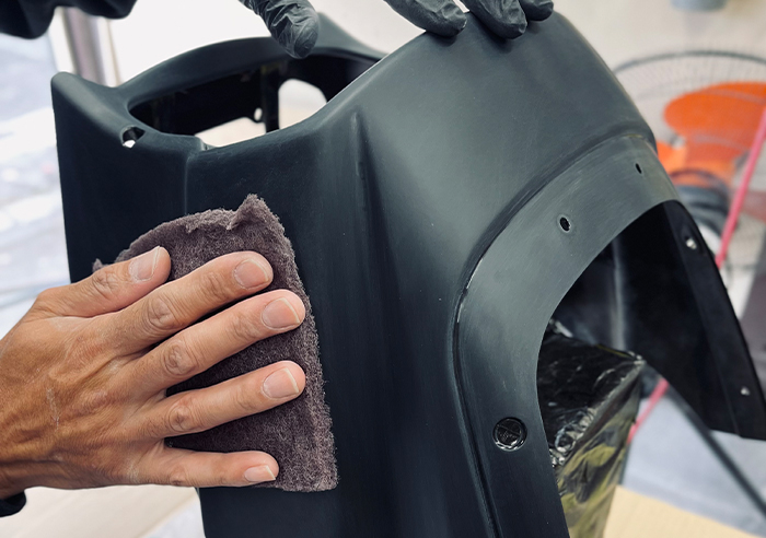 塗料の密着性を高めるため、バイクパーツ表面に下地処理を施す作業工程